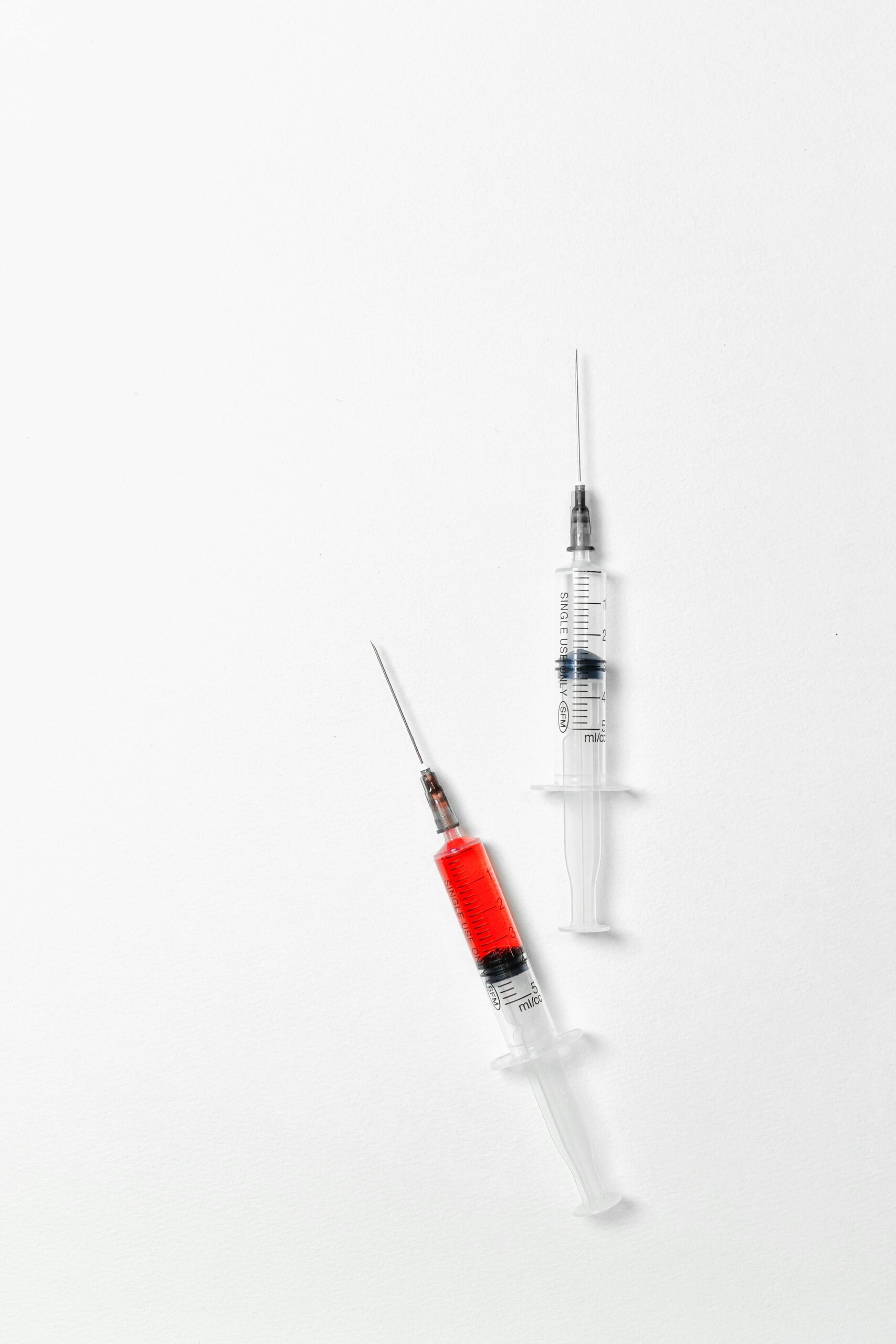 Two medical syringes on white background inspired by the GLP-1 injections like Ozempic and Wegovy, commonly used for weight loss and type 2 diabetes treatment.