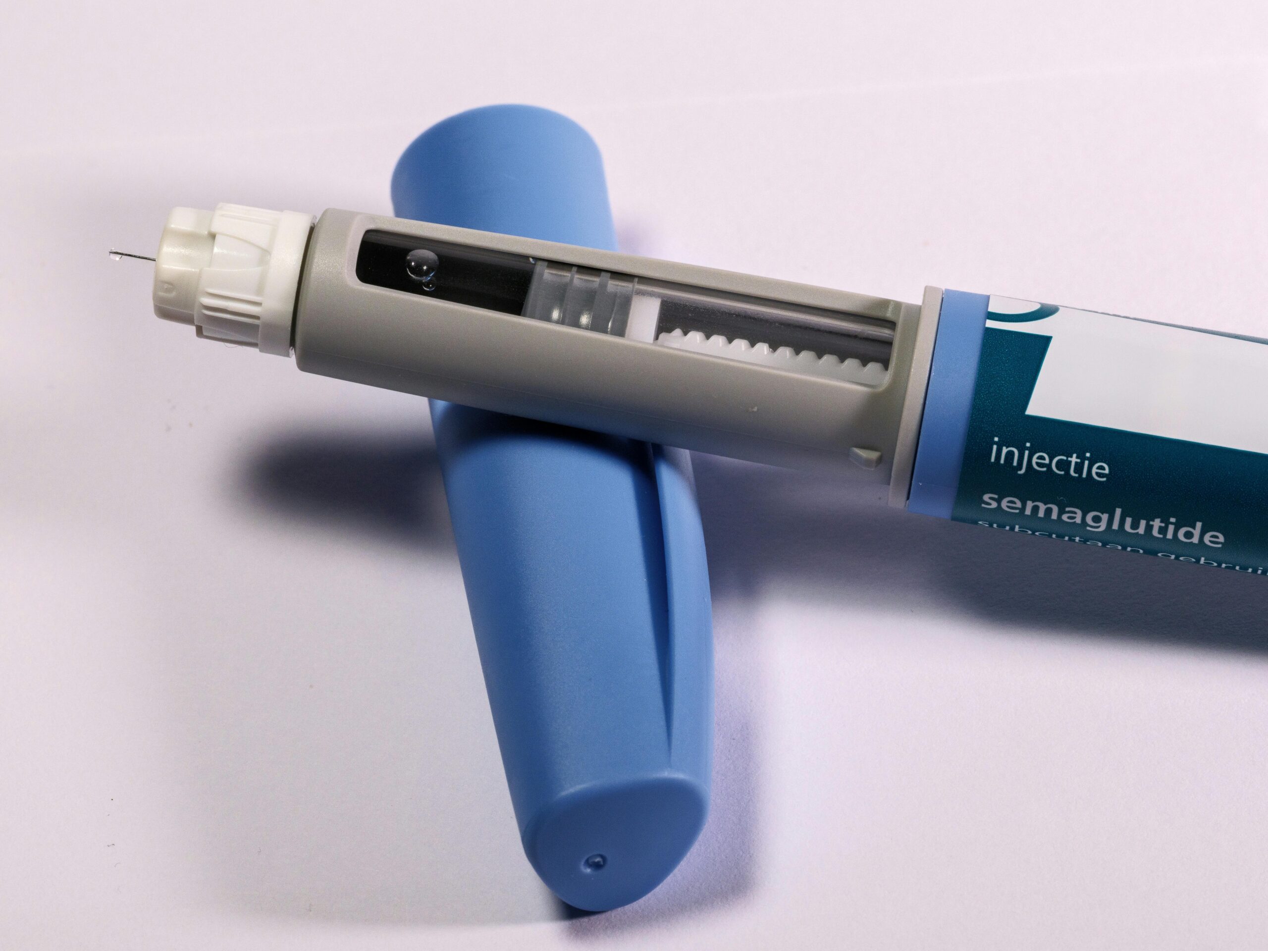 Close-up of a semaglutide injection pen with a visible needle and blue cap, used for weight loss and blood sugar management.
